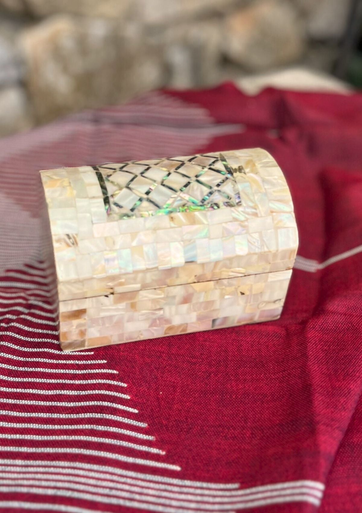 Boîte en bois et nacre, de marqueterie posée sur un châle de couleur bordeaux tissé main